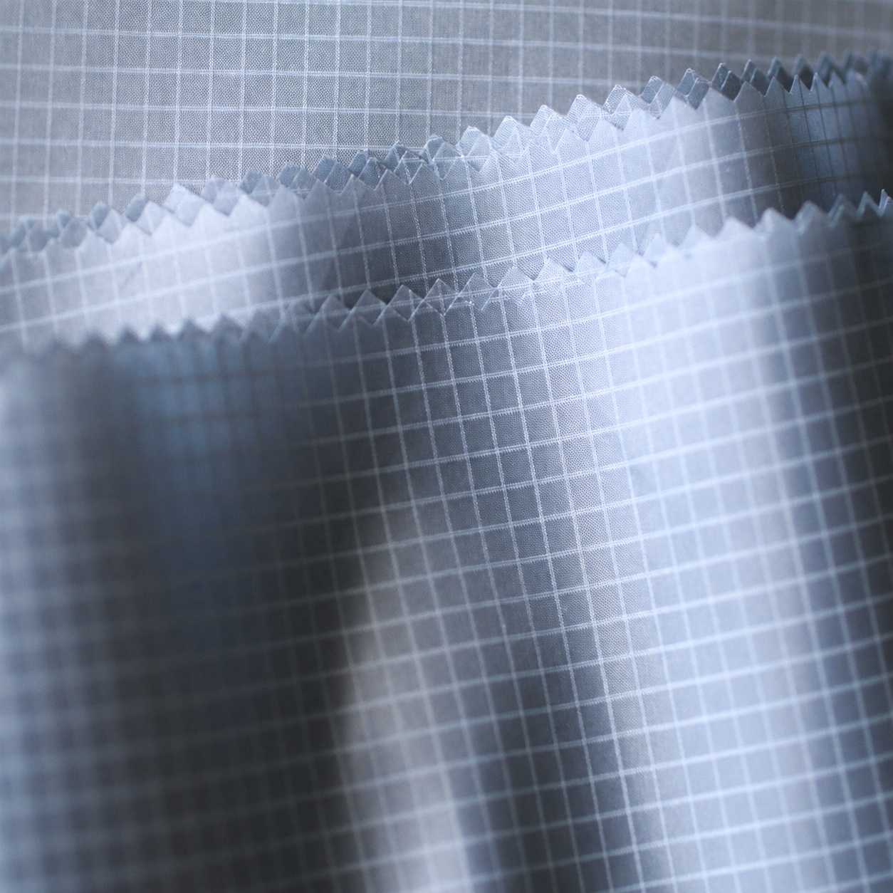 Overlapping pale blue-gray fabric swatches with a visible square grid.