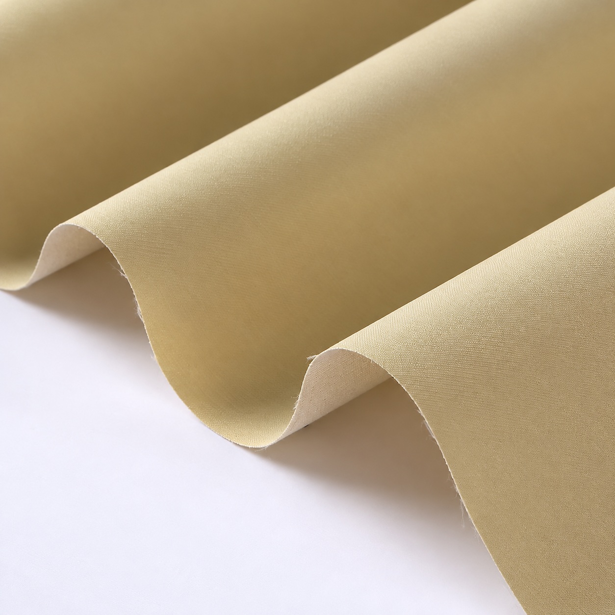 Beige fine-textured fabric arranged in two rolled folds.