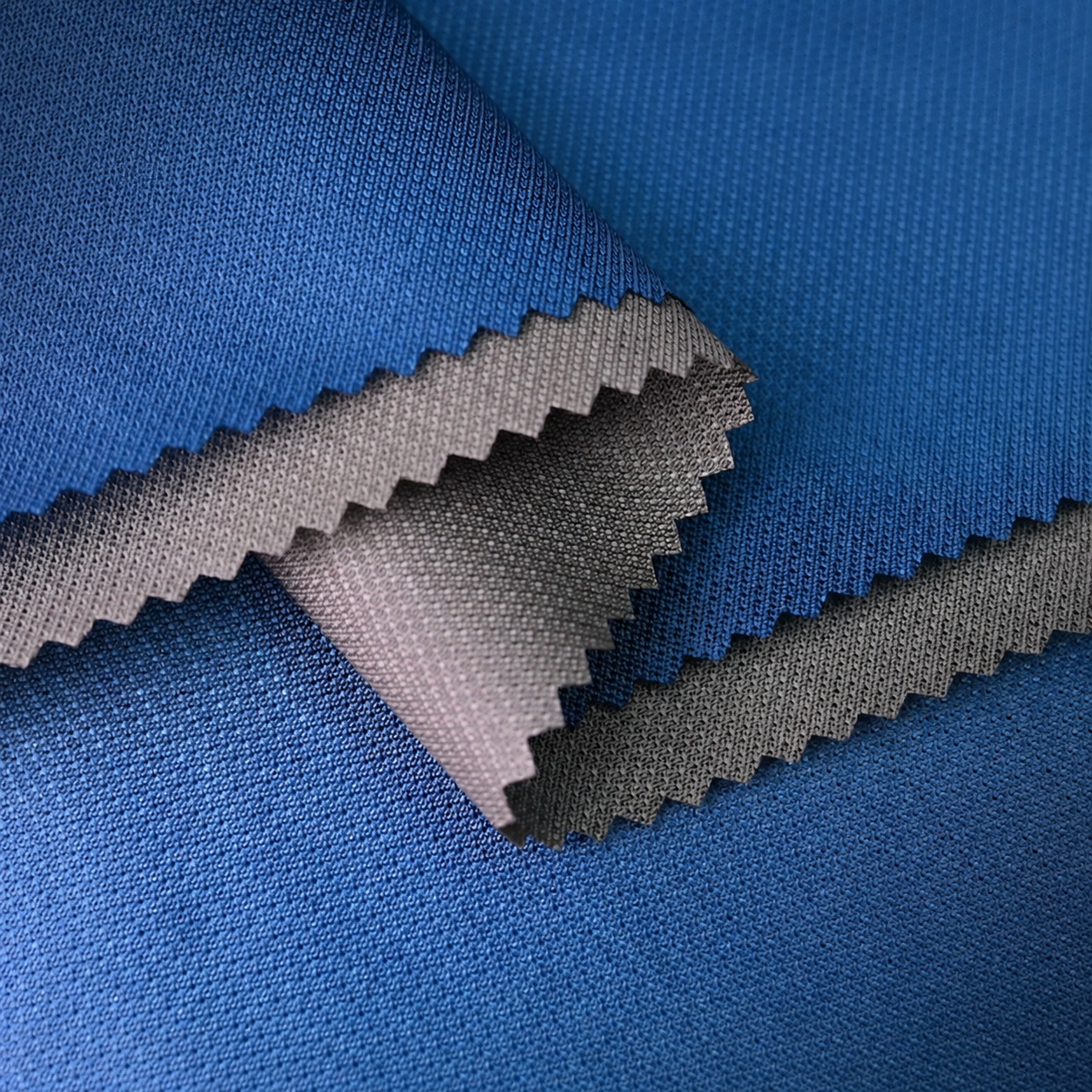 Blue and gray textured fabric samples with overlapping folds and zigzag-cut edges.
