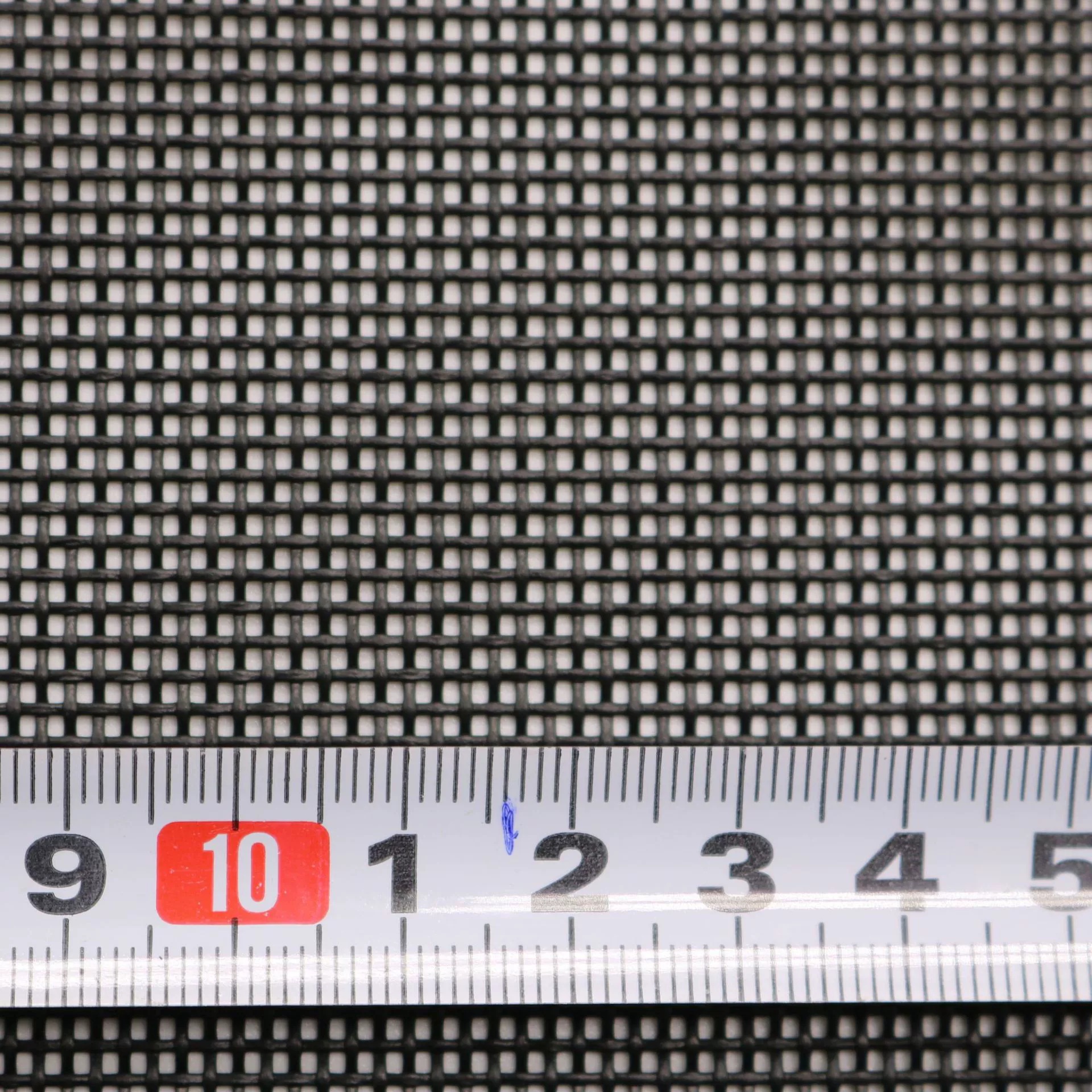 Close-up of dark square mesh with a measuring tape placed across the lower portion.