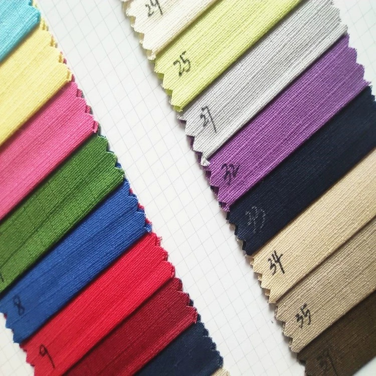 A fan of colored cotton fabric samples with zigzag-cut edges arranged on gridded paper.