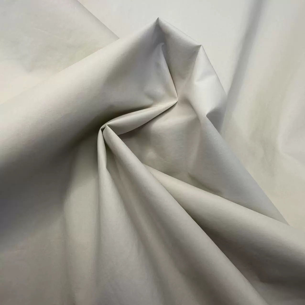 Beige-gray lightweight fabric gathered into angular folds.