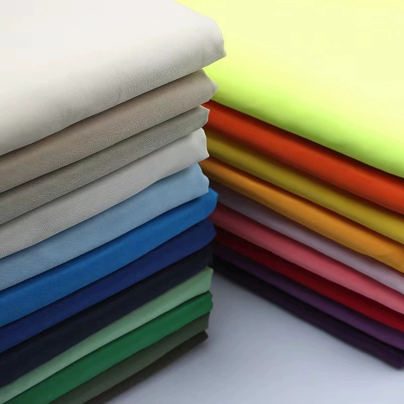 Stacks of folded fabric in neutral, blue, green, yellow, red and orange colors.