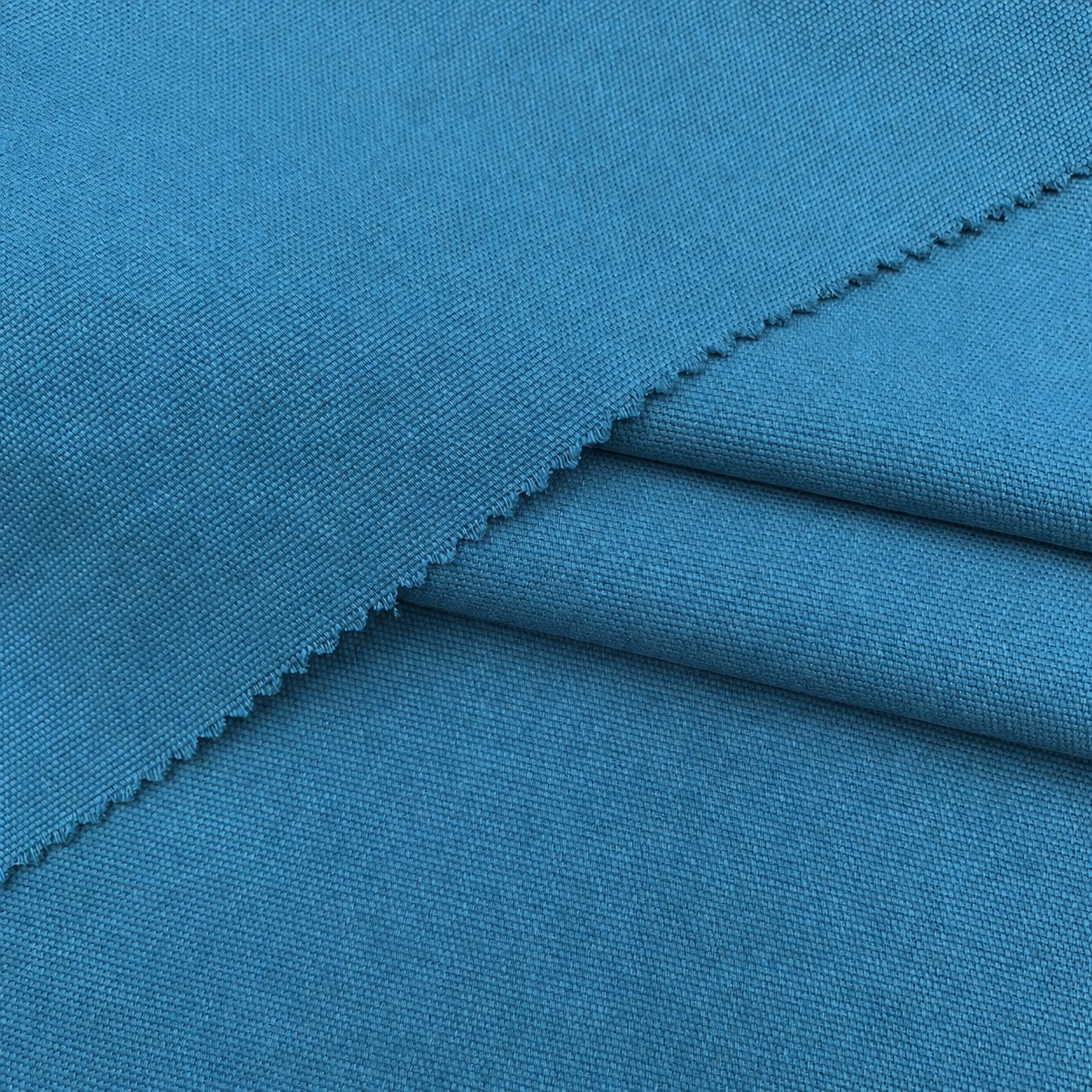 Blue woven cotton canvas with a zigzag-cut folded edge and visible surface texture.