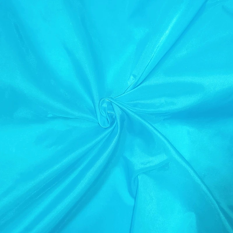 Turquoise-blue lightweight fabric arranged in a loose spiral fold.