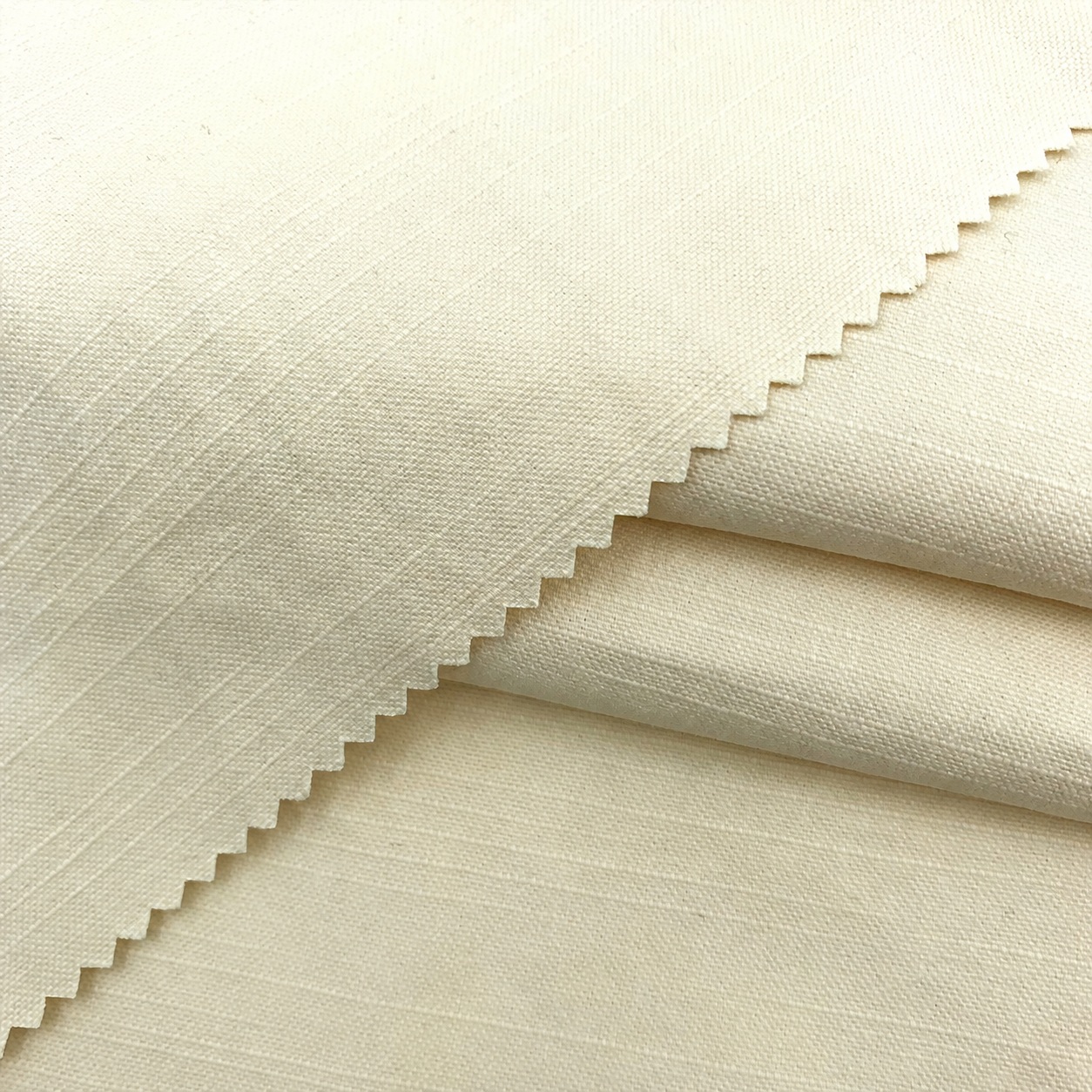 Cream-colored cotton fabric with subtle slub lines and a zigzag-cut folded edge.